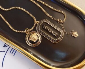 سلسلة ذهبية بتصميم مستوحى من Versace مع تعليقة ميدوسا ونقشة يونانية.